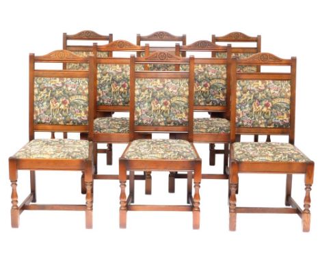 A set of eight oak dining chairs, each with tapestry seats, comprising two carvers, 104cm high, 50cm wide.  The upholstery in
