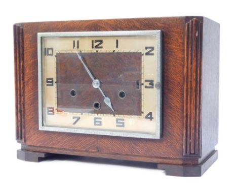 A 1930s oak cased mantel clock, with a silvered coloured numeric dial in a chrome outer casing on bracket feet, 23cm high, 33