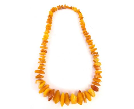 A butterscotch amber necklace, with various faceted light and dark coloured amber beads, on a knotted string strand, 62cm lon