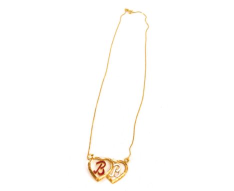 An enamel and yellow metal pendant and chain, the two adjoining heart pendant bearing the initials BB in red and white enamel