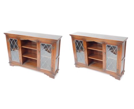 A pair of Old Charm oak cabinets, with two astragal glazed doors and central bookshelf section, on bracket feet, 83cm high, 1
