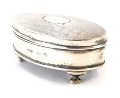 A George V silver oval dressing table box, with engine turned decoration, vacant oval reserve to lid, with turquoise silk lin