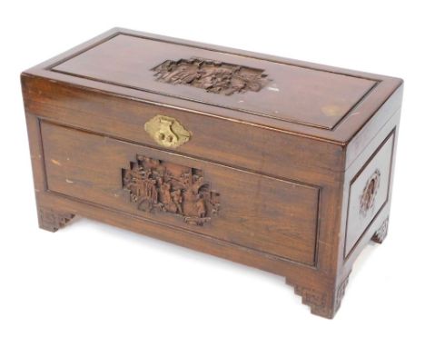 An early 20thC Chinese camphorwood chest, carved to the lid and front with landscapes and figures in bass relief, the sides w