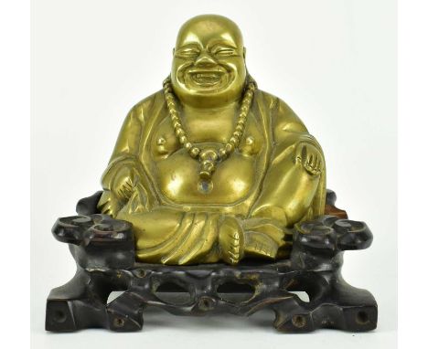 A late Qing/ early Republic period bronze figure of Laughing buddha, modelled seated with a laughing expression, on a carved 