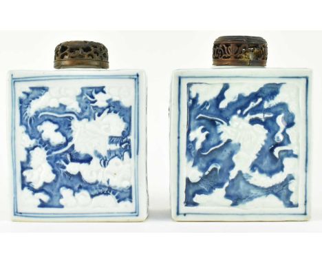 Two Qing dynasty blue and white tea caddies, each reatangular caddy decorated with relief moulded dragons amidst clouds with 