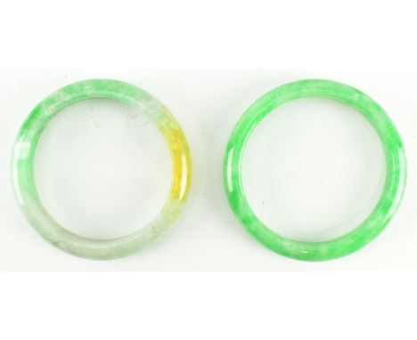 Two jade bangles. The lot to include a tri-colour bangle, size 57/58mm and a gree colour bangle, size 60mm.Larger iner diamet