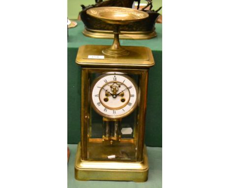 A brass four glass striking mantel clock, circa 1890, bevelled glass panels, surmounted by a pedestal bowl, 4-1/4-inch enamel