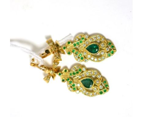 A pair of emerald and diamond earrings, a round brilliant cut diamond set yellow bow suspends a fancy drop set centrally with