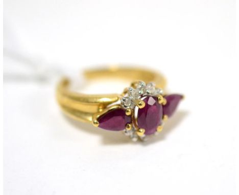 A ruby and diamond ring, an oval cut ruby within a border of eight-cut diamonds and flanked by pear cut rubies in yellow claw