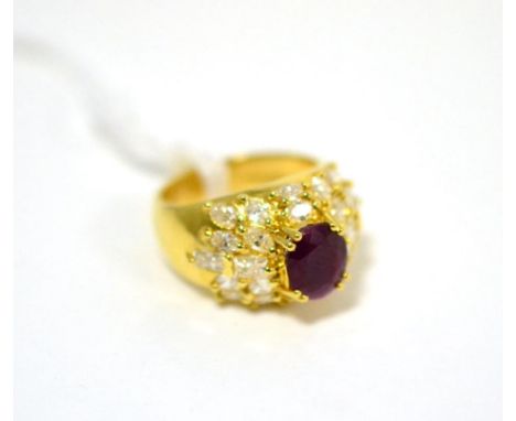 A ruby and diamond cluster ring, an oval cut ruby in a yellow claw setting within a border of marquise cut and baguette cut d