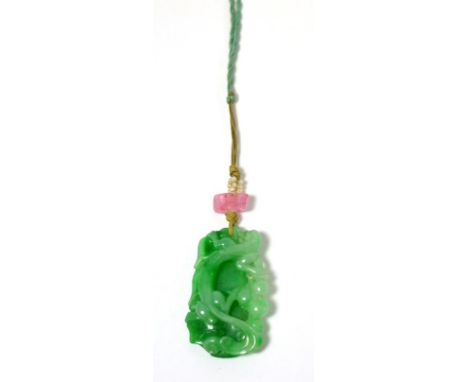 A carved jade pendant, depicting fruiting vines, strung with a pink stone and seed pearls, on a green cord, jade measures 3.3