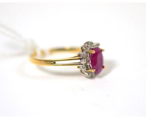 A ruby and diamond cluster ring, an oval cut ruby in a yellow claw setting within a border of round brilliant cut diamonds, t