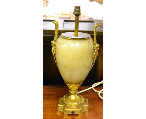 A gilt metal mounted onyx lamp base, in Regency style, of ovoid form with loop and mask handles on stiff leaf cast socle and 