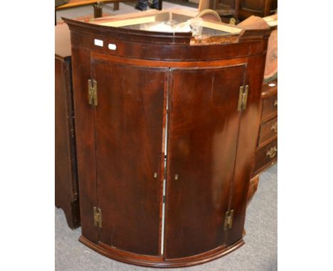 ^A George III mahogany bow fronted corner cupboard