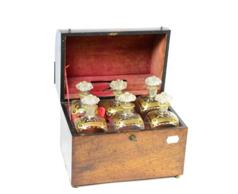 A 19th century mahogany domed top decanter box, enclosing six gilt decorated decanters with stoppers, 29 cm wide Exterior of 