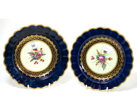 A pair of First Period Worcester porcelain plates painted with flowers on a blue and gilt ground, 21.5cm diameter; a similar 