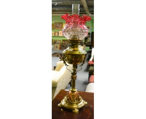 A late 19th century brass oil lamp with cranberry shade Metal base with accumulated traces of metal polish in fine detail. Fi