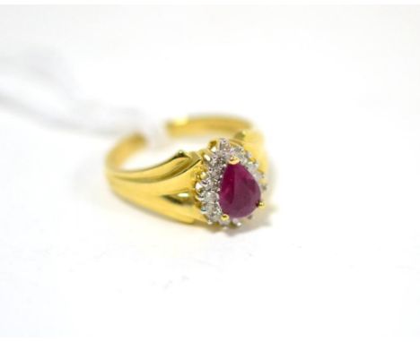 A ruby and diamond ring, a pear cut ruby in a yellow claw setting within a border of eight-cut diamonds, to fancy yellow shou