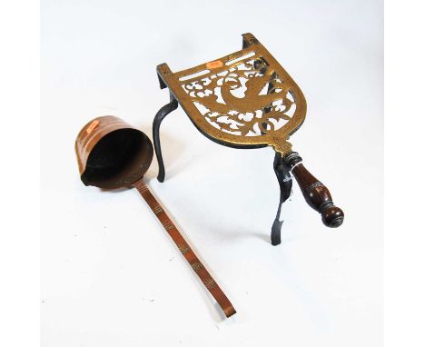 A 19th century pierced brass trivet, having turned mahogany handle, on wrought iron supports; together with a copper ladle (2
