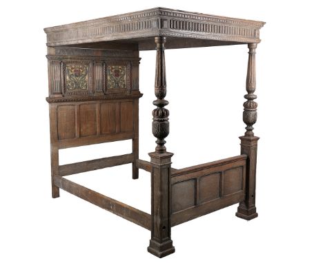 A CHARLES II STYLE OAK TESTER BED. having gadrooned cup and cover supports above a panelled tester and headboard, 219cm high 