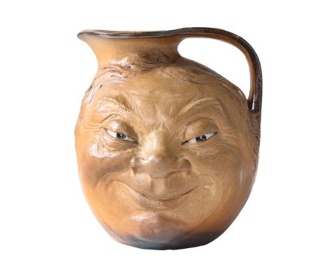 ROBERT WALLACE MARTIN (1843-1923) FOR MARTIN BROTHERS. A STONEWARE 'FACE' JUG (1910), Each side modelled with a grotesque smi