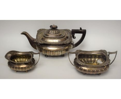 A George V silver three piece half fluted boat shaped tea service, comprising teapot, milk jug and sugar basin, hinged domed 