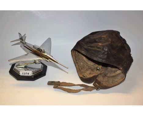 A World War Two period leather flight helmet, ear apertures; a novelty desk lighter, as a jet (2)