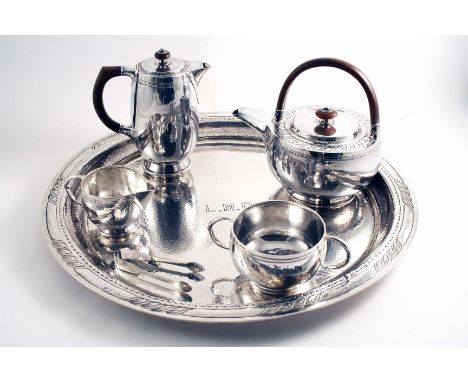 BY LIBERTY & CO.:- An early 20th century four-piece tea set with squat circular bodies, chased borders and a hammered finish,