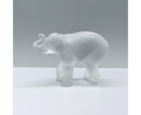 A small, frosted crystal elephant figurine stands gracefully on all fours, her trunk delicately raised, embodying an aura of 