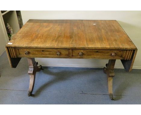 A William IV rosewood sofa table having two short drawers standing on rectangular and gadroon pillars, splayed legs with lion