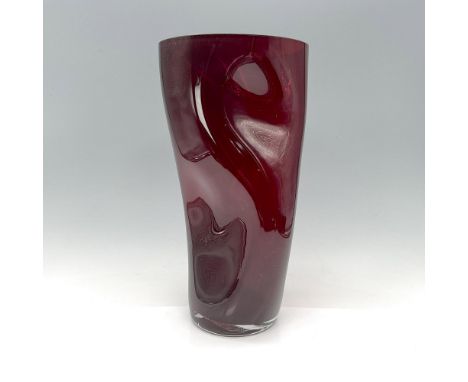 The unique design of Orrefors' Squeeze vase, crafted in ruby red, offers a dynamic visual experience, appearing differently f