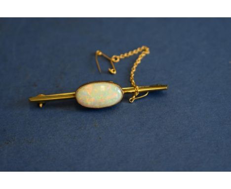 A 9ct gold bar brooch set central oval opal. 