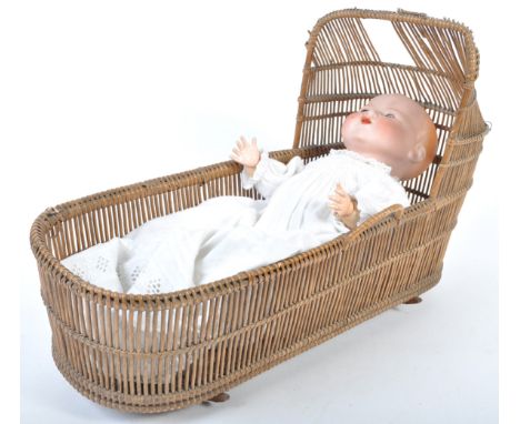 An early 20th Century antique German Armand Marseille bisque headed doll / baby within a period wicker cradle. The dolls face