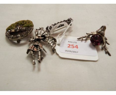 A group of four silver brooches to include an Art Deco circular brooch set with paste and agate, Scottish piper, Scottish sta