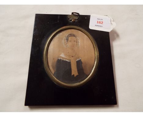 A Victorian watercolour on paper portrait miniature of a lady, set into brass and ebonised silhouette frame
