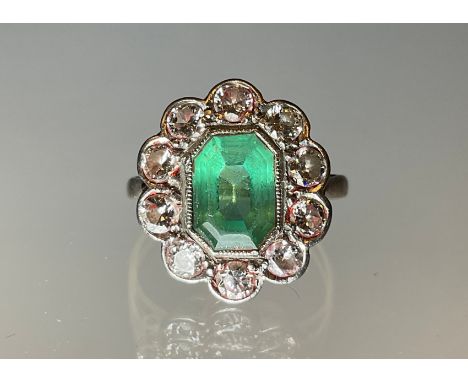 An emerald and diamond cluster ring, central step cut mid tone emerald, approx 9mm x 7mm x 5mm, estimated emerald weight appr