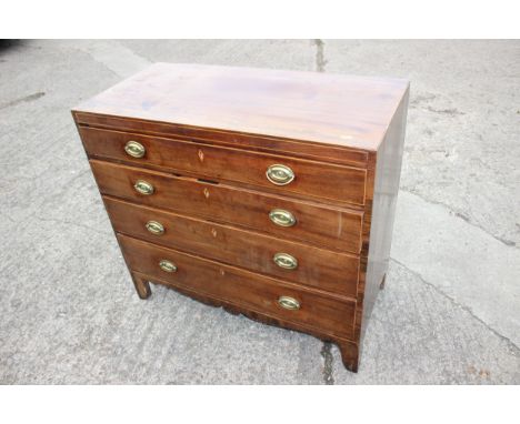 An early 19th century mahogany and box line inlaid chest of four graduated long drawers with stamped brass handles, on bracke