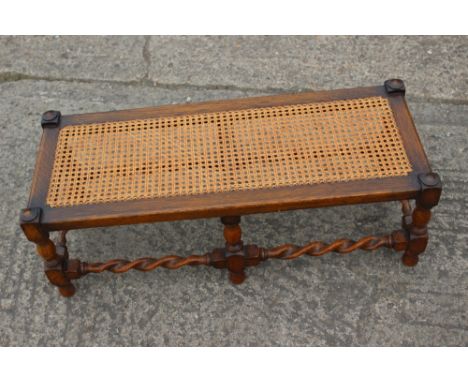 A cane seat stool of Restoration design, on barley twist stretchered supports, 30" wide x 12" deep x 10" high