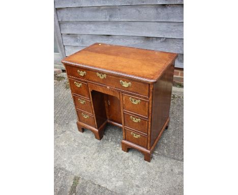 A George II walnut kneehole desk with quarter veneered top, fitted one long drawer over central cupboard, flanked by six draw