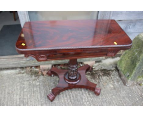 An early 19th century figured mahogany fold-over top card table, on acanthus carved turned column and quatreform base with sc