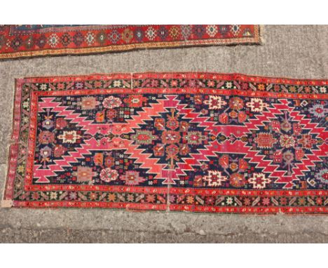 A Kazak runner with two diamond lozenges on a blue ground and star borders, 102" x 38 1/2" approx (worn)
