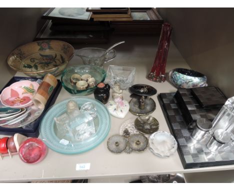 A miscellaneous shelf including paperweights, glassware, and brass