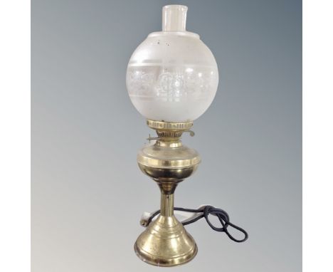 A vintage brass oil lamp with chimney and shade, electrified.