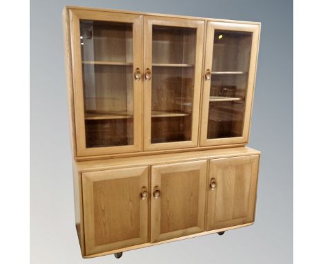 An Ercol Windsor elm and beech triple door glazed bookcase fitted with cupboards beneath 