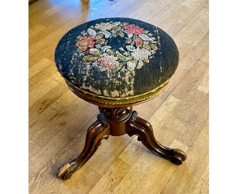 A Victorian carved walnut piano stool with adjustable revolving seat height, upholstered tapestry seat on a tripod base. 