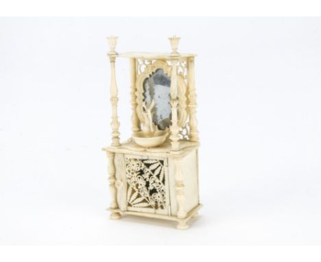 A 19th century dolls’ house bone washstand, with turned column supports, base with cupboard, mirror set in back and turned ju