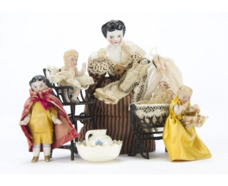 Dolls’ house dolls: a china shoulder-head with black painted bun, in brown striped dress and holding baby - 4¾in. (12cm.) hig