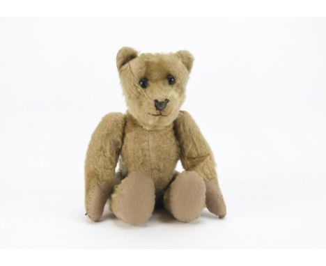 An early teddy bear, possibly American 1910-20s, with dark blonde mohair, black boot button eyes, pronounced upturned muzzle,