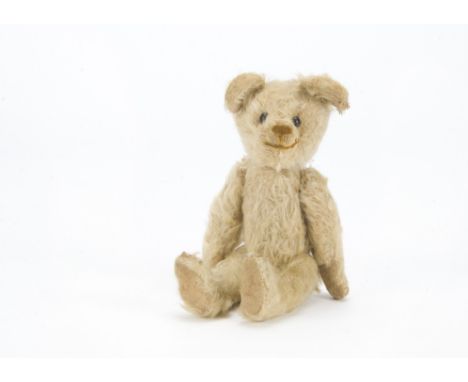 An early British teddy bear 1920s, with white mohair, black boot button eyes, brown stitched nose and mouth, swivel head, pin