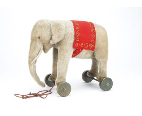 A Steiff elephant on wheels, 1920s, with grey mohair, black boot button eyes with red felt behind, white felt tusks, embroide